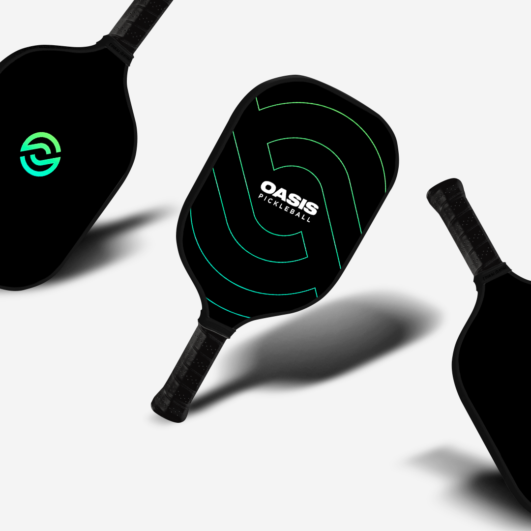Three pickleball paddles with black grips and black textured faces with green accent lines. The brand logo 'OASIS' is visible on two of the paddles.